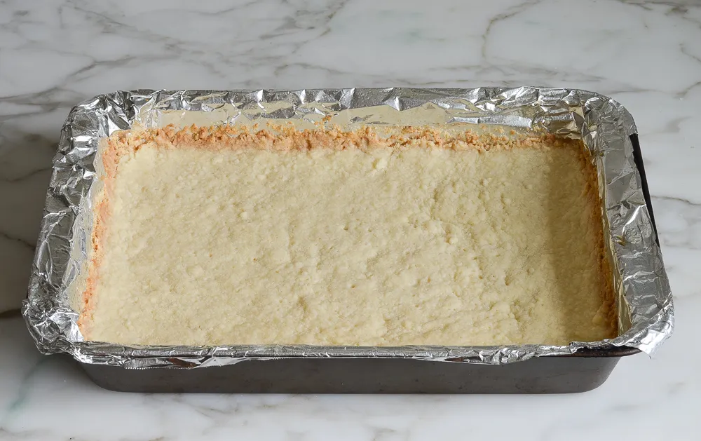 lemon bar in baking tray after being frozen-kookybakes.com