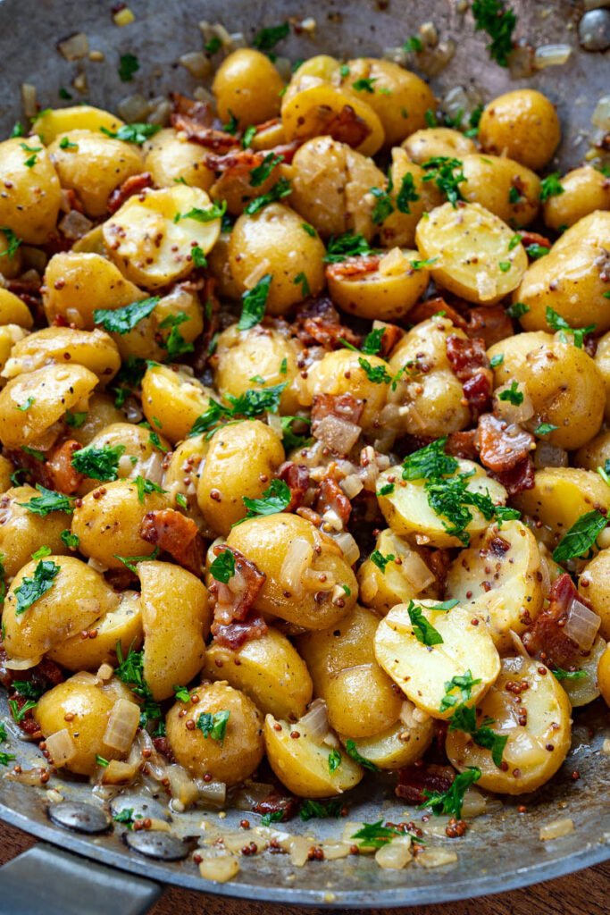 roasted german potato salad in bowl served with herbs-kookybakes.com