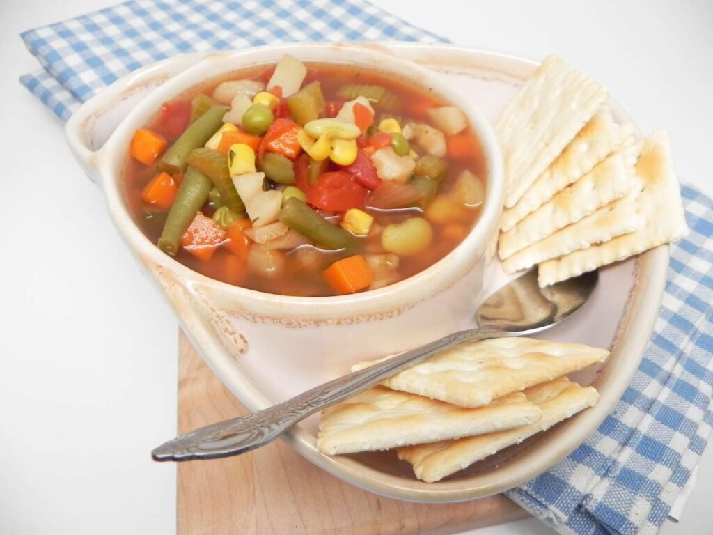 vegetable soup served with savory crackers in bowl-kookybakes.com